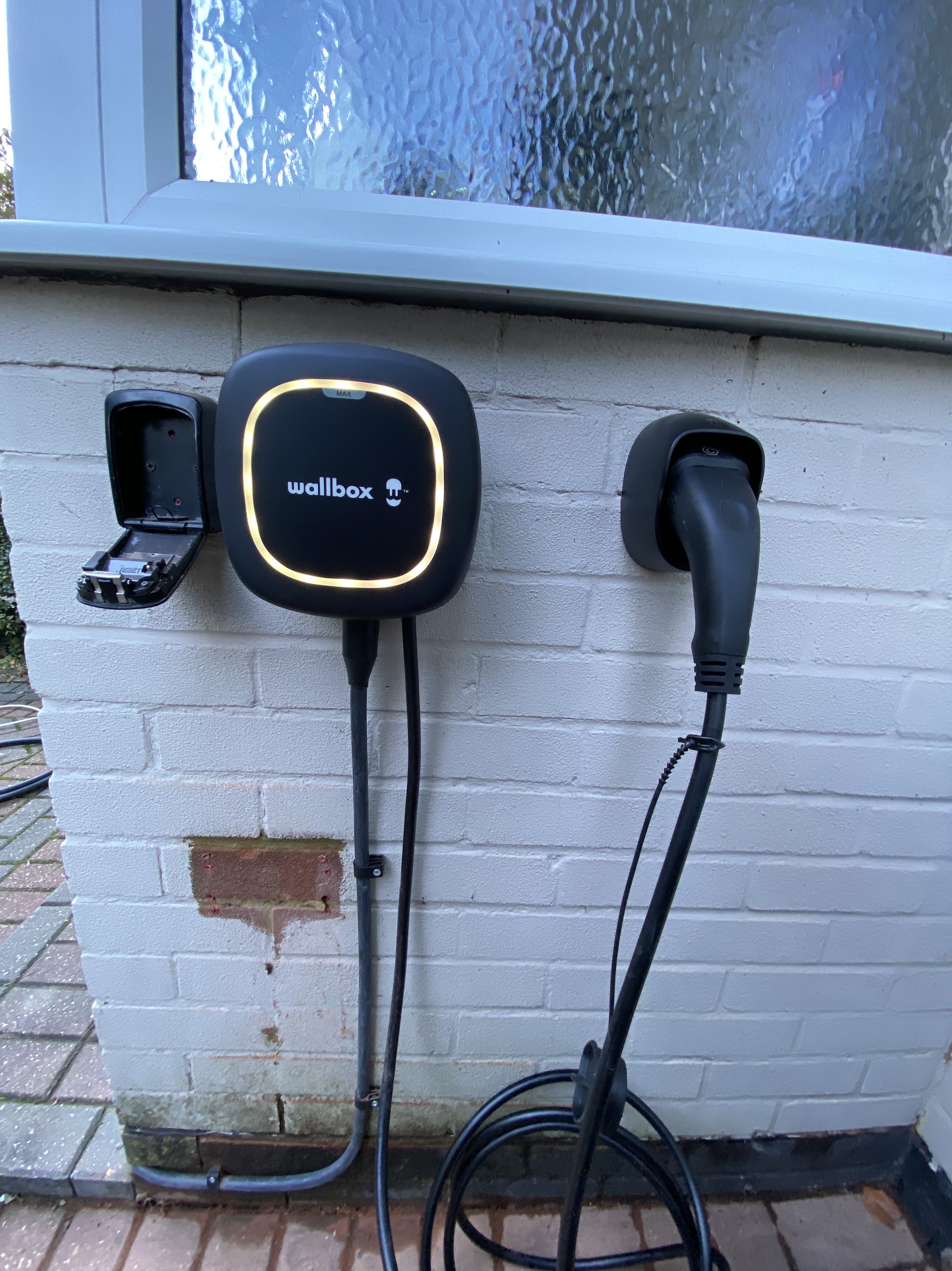 Wall-mounted car charger on a white painted garden wall